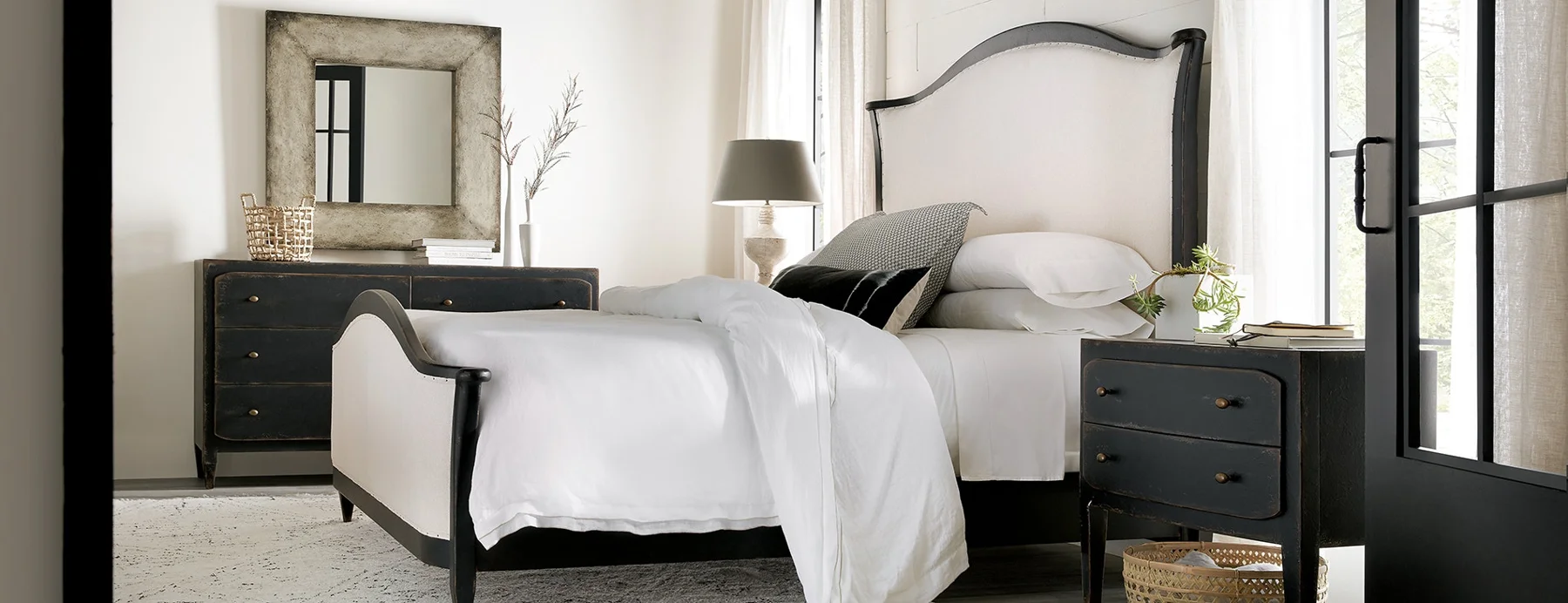 Layered neutral bedroom with an upholstered bed and dark wood furnishings